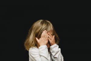 child covering face with hands